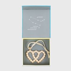 an open box with a heart shaped beaded necklace in the front and inside it