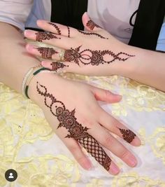 two hands with henna tattoos on them