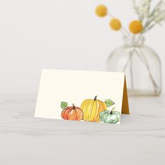 a card with pumpkins on it sitting next to a vase