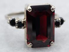 A luxurious combination of gleaming white gold, a captivating emerald cut garnet, and alluring black diamond accents come together in this beautiful ring. Show off with some seriously sparkly style! Metal: 14K White Gold Gem: Garnet 8.34 Carats Gem Measurements: 9.2 x 14.1 mm, Emerald Cut Accents: 4 Diamonds totaling .40 Carats, I in Clarity, Black in Color Ring Size: 7.75 SKU #: A36159 Each piece has been identified and graded by a Graduate Gemologist who has been certified by the Gemological I Gold Garnet Ring, Demantoid Garnet, Estilo Real, Tsavorite Garnet, Black Diamond Ring, Garnet Jewelry, Garnet Ring, Garnet Rings, Color Ring