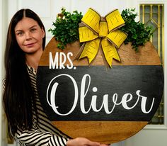 a woman holding a wooden sign that says mrs cleverer with a bow on it