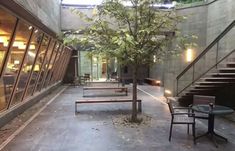 an empty courtyard with benches and tables next to the stairs leading up to some windows