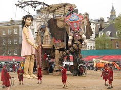 an elephant statue is being displayed in front of some children and adults at a festival