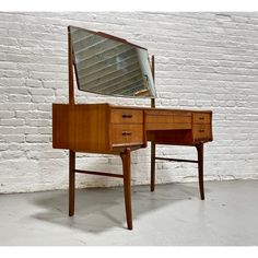 a desk with a mirror on top of it next to a brick wall and floor