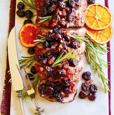 meat with cranberry sauce and oranges on a cutting board