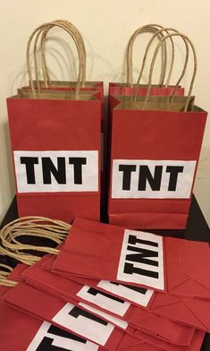 two red bags with white and black letters on them sitting on a table next to some twine