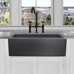 a kitchen sink with two faucets in front of three windows overlooking the mountains