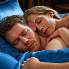 a man and woman are sleeping together on a blue comforter with their eyes closed