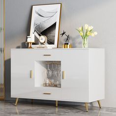 a white sideboard with gold handles and drawers in a living room next to a painting