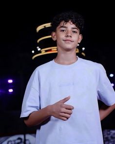 a young man standing in front of a microphone and wearing a white t - shirt