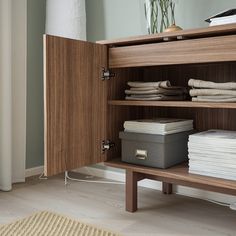 a wooden cabinet filled with lots of white towels and folded linens on top of it