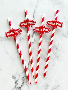 three red and white striped paper straws with north pole stickers on the top