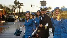 a group of women in blue uniforms are walking down the street with their suitcases