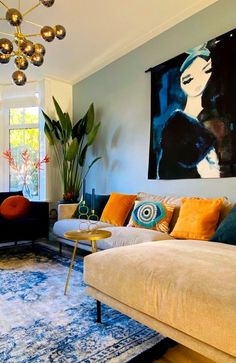 a living room filled with furniture and a large painting hanging on the wall above it