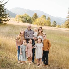 a family poses for a photo in a field with mountains in the background