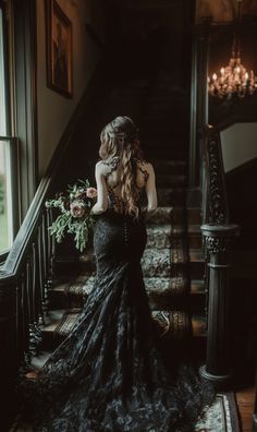 a woman in a black dress is walking down the stairs with her back to the camera