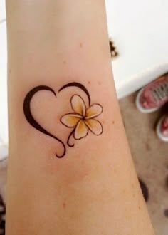 a heart shaped tattoo with a flower on the wrist