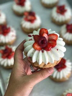 a person holding up a pastry with strawberries on top