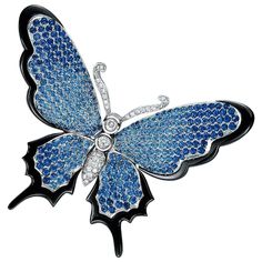 a blue butterfly brooch with diamonds on it's wings, sitting in front of a white background