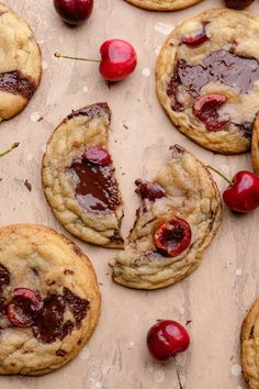 chocolate chip cookies with cherries are arranged on a table