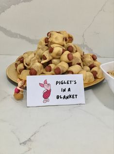 a pile of pigs in a blanket cookies on a plate with a sign that says, piglet's in a blanket