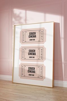 three movie tickets sitting on top of a wooden floor in front of a pink wall