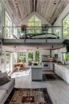 an open concept living room and kitchen in a loft style home with high ceilings, hardwood flooring, white painted walls and wooden beams on the ceiling