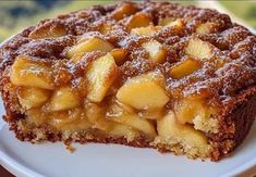 a close up of a piece of cake on a plate with powdered sugar and apples