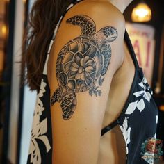 a woman's arm with a turtle tattoo on the back of her left shoulder