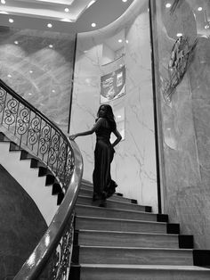 a woman in a long dress walking down some stairs