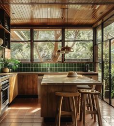 a kitchen with wooden cabinets and green tile on the walls, along with two stools