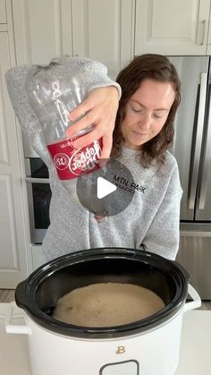 a woman pouring water into a crock pot with the lid open and in front of her