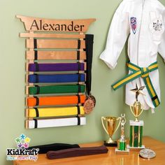 a wall mounted rack with karate belts and medals on it next to a wooden table