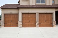 three brown garage doors in front of a house