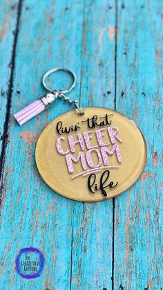 a keychain with the words give that cheer mom life written in pink on it