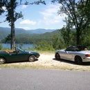 two cars parked next to each other on the side of a road in front of trees