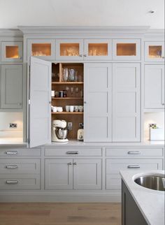 an open cabinet in the middle of a kitchen with lots of cupboards and drawers