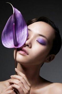 a woman with purple eyeshades holding a flower