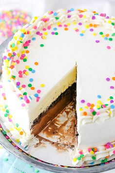 a cake with white frosting and colorful sprinkles on the top is cut in half