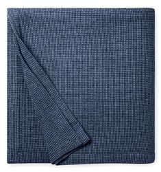 a blue blanket folded on top of a white table with an empty napkin underneath it