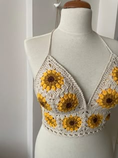 a white mannequin with yellow flowers on it's chest and two crocheted straps