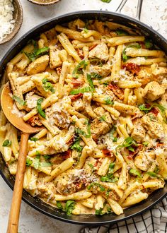 a skillet filled with pasta, chicken and parmesan cheese