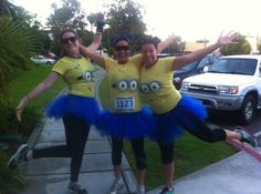 three women dressed in costumes posing for a photo on the sidewalk with their arms up