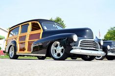 an old black car with wood trim parked on the street