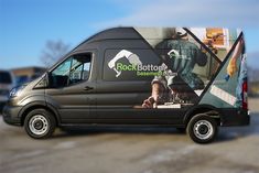 a black van parked in a parking lot next to other cars and trucks with advertisement on the side