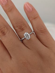 a woman's hand with a diamond ring on her left hand and the other hand holding an engagement ring