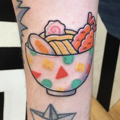 a person with a tattoo on their arm has a bowl of noodles and candy in it