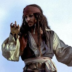 a man with dreadlocks is dressed in pirate attire and holding his hands up