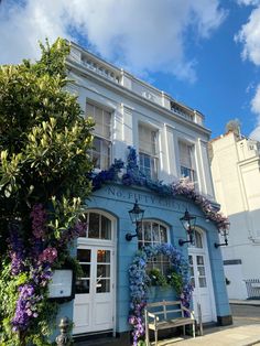 a blue building with lots of flowers on the front and side of it's windows