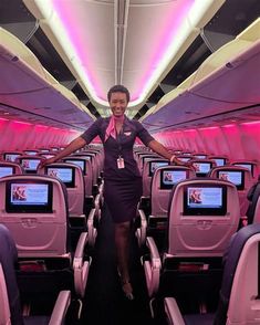 a woman standing on the aisle of an airplane with her arms spread out in front of her